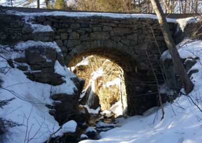 Small bridge with a small underpass surrounded by snow.