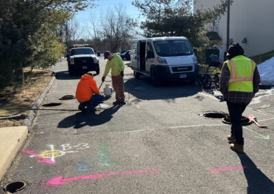 Workers scanning the street and marking the ground with orange and white arrows.