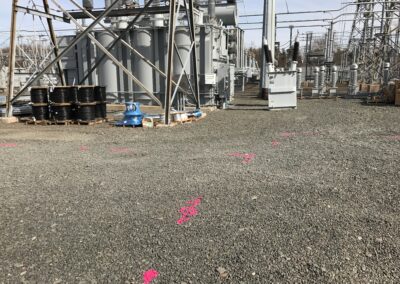 An electrical plant with transformers and orange markings on the ground.
