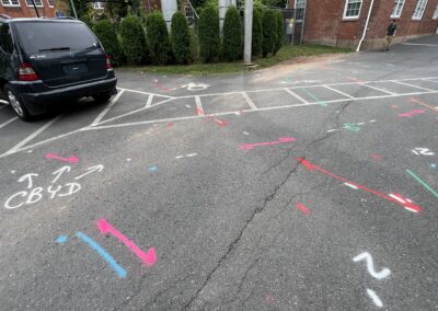 A driveway with blue and orange markings on the ground with a parked black van in the corner.