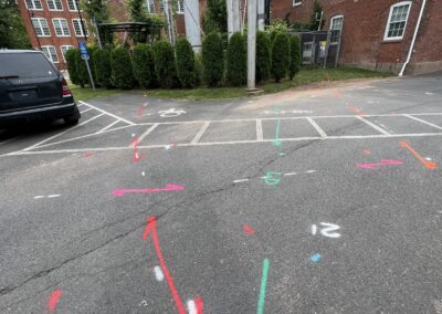 A driveway with blue and orange markings on the ground with a parked black van in the corner.