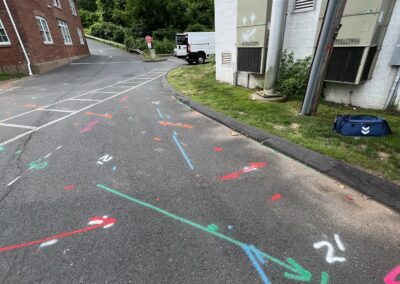 A driveway with blue and orange markings on the ground with a parked white van in the corner.
