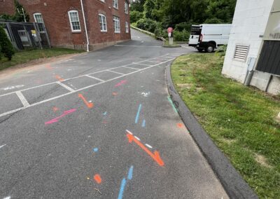 A driveway with blue and orange markings on the ground with a parked white van in the corner.