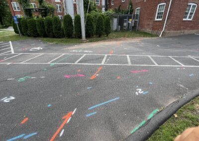 A driveway with blue and orange markings on the ground behind the brown bricked house.