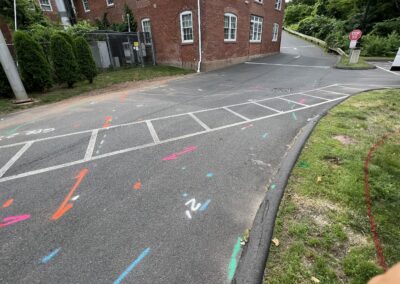 A driveway with blue and orange markings on the ground with a parked white van on the right side of the corner.