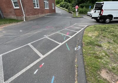 A driveway with blue and orange markings on the ground with a parked white van on the right side of the corner.